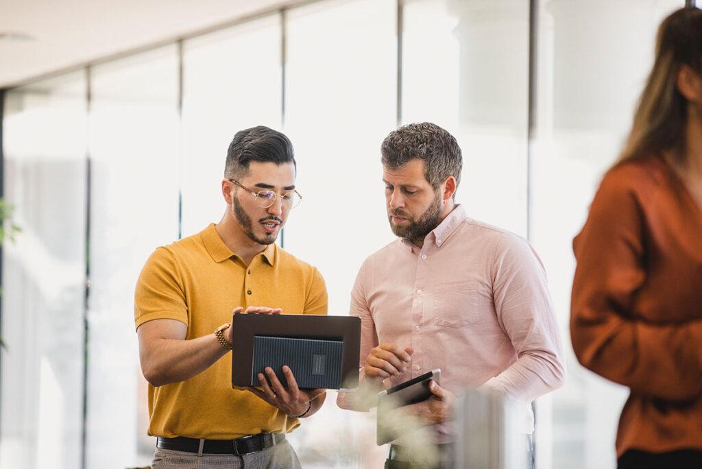 Two men at work look at iPad together