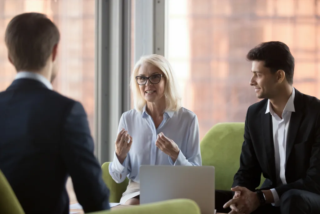 Business woman in white shirt discussing cyber strategy with two men in blue suits