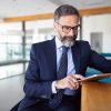 Man in suit sat looking at iPad